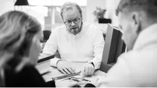 Drei Personen besprechen gemeinsam Unterlagen an einem Tisch